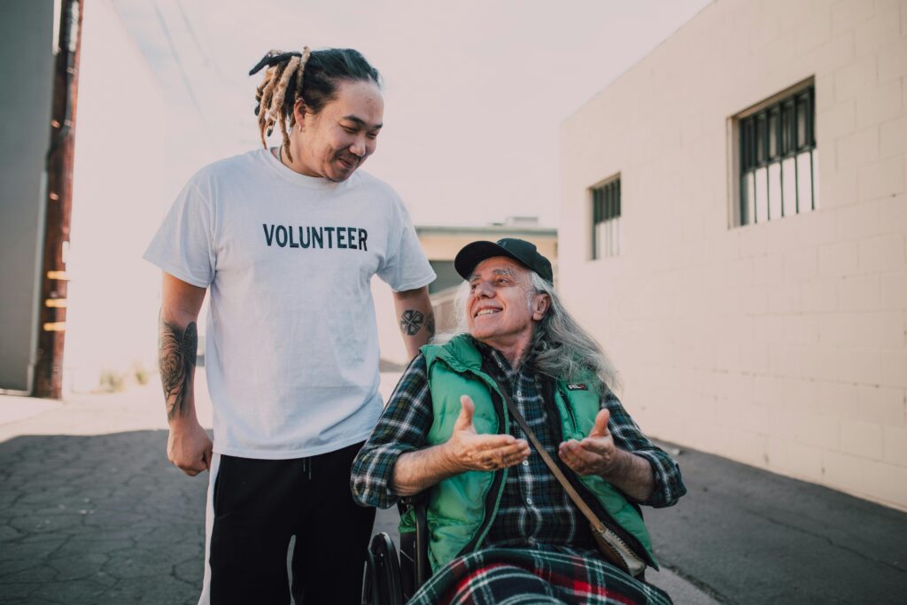 A man walking beside another man in a wheelchair as they talk.