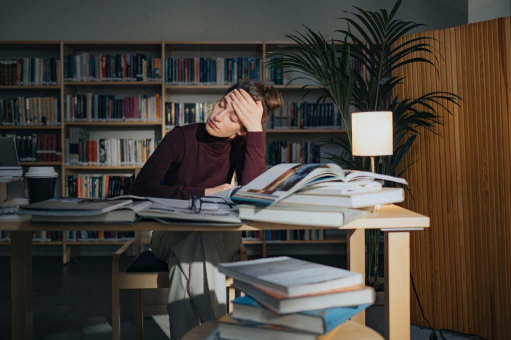 A woman sitting at a desk with her head in her hands. 
