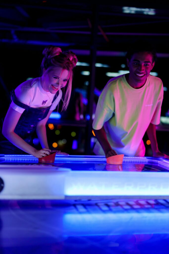 Two people playing air hockey together.